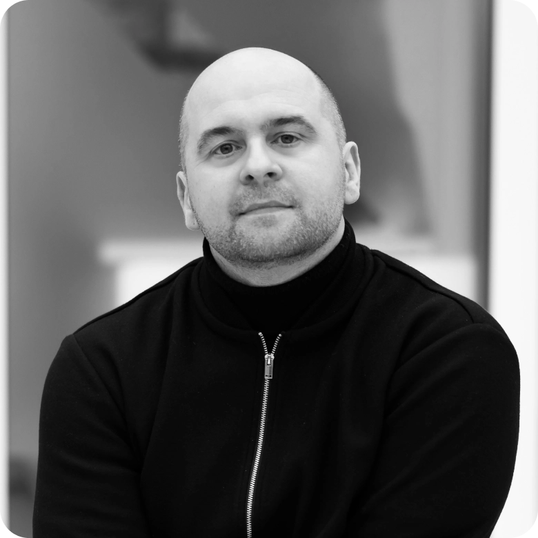 Prof. Šarūnas Grigaliūnas, Head of the National Cyber Security Centre of Excellence at KTU. Portrait photograph of a man with closely cropped hair wearing a dark high-neck sweater. He is seated facing the camera with a softly blurred indoor background.