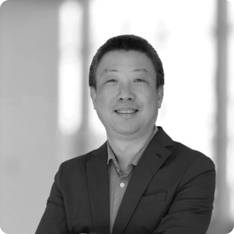 Lu Dai, Vice President of Technical Standards at Qualcomm Technologies, Inc. portrait photograph of a man in a suit in front of a blurred background