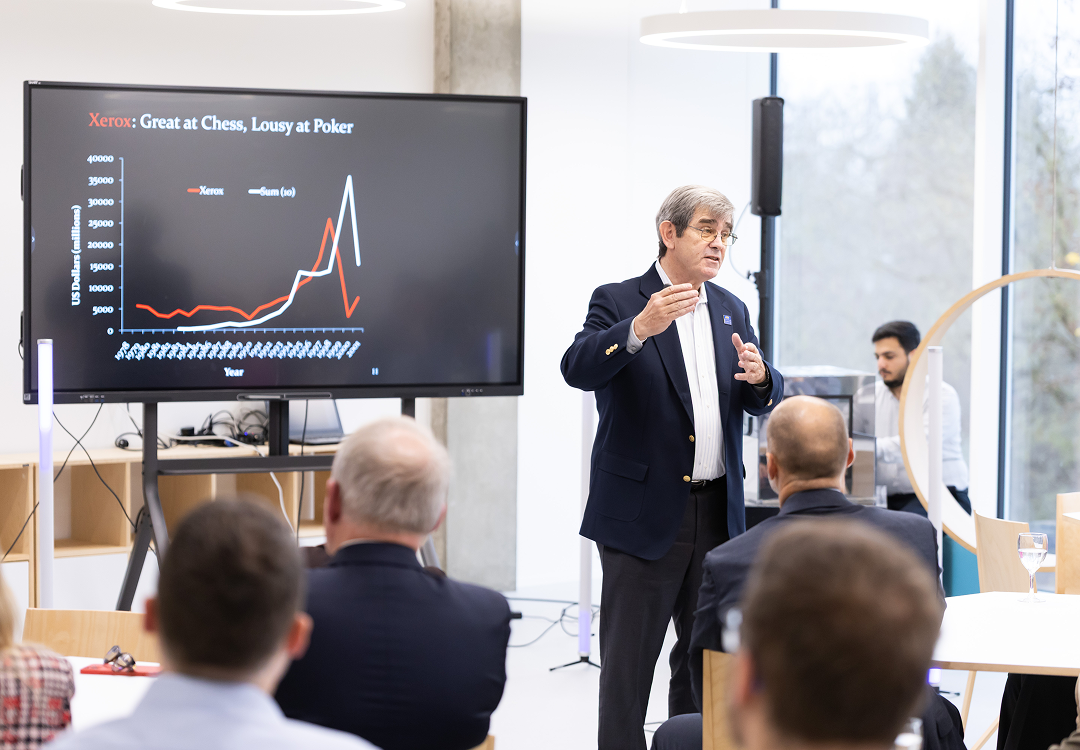 OIC for Challenge framing with open innovation experts A man delivers a presentation to an audience, gesturing beside a large screen displaying a line graph about Xerox.