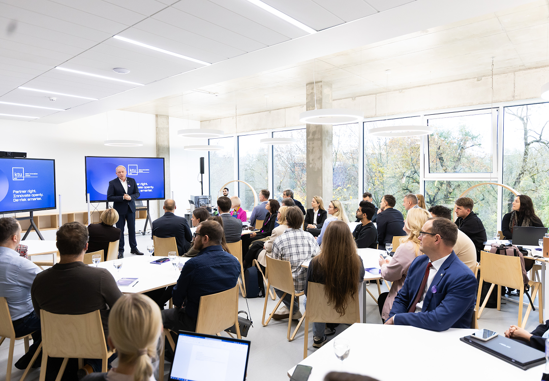 OIC for Executive learning & innovation capacity building A speaker addresses an audience seated at tables in a bright, modern conference room, with KTU Open Innovation Centre branding displayed on screens.