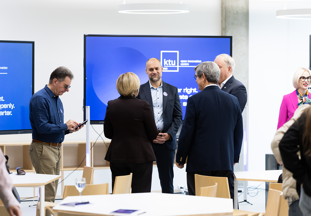 OIC for Strategic innovation orientation Group of professionals standing and talking in front of a screen displaying the KTU Open Innovation Centre branding.